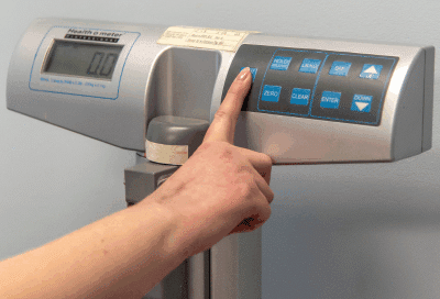Closeup of a person pressing a button on a scale, representing weight loss clinic in salem va