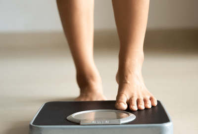 Person stepping on a bathroom scale, representing sustainable weight loss with physician support at the weigh station in salem, va.
